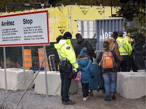 In this file photo, a family claiming to be from Colombia is arrested by RCMP officers as they cross the border into Canada from the United States as asylum seekers on April 18, 2018 near Champlain, N.Y.