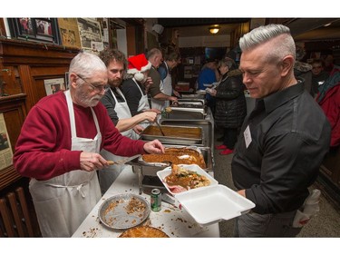 Volunteers dish up plates of turkey as the annual Carleton Tavern Christmas Dinner was held from 11am to 3pm with about 120 volunteers taking turns serving meals to anyone who wanted to come in and enjoy some company, live music and roast turkey with all the trimmings including dessert.  Photo by Wayne Cuddington/ Postmedia