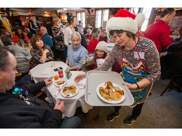 Volunteer Robin Gaines delivers plates of food as the annual Carleton Tavern Christmas Dinner was held from 11am to 3pm with about 120 volunteers taking turns serving meals to anyone who wanted to come in and enjoy some company, live music and roast turkey with all the trimmings including dessert.  Photo by Wayne Cuddington/ Postmedia