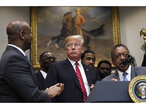 President Donald Trump attends a ceremony for the signing of an executive order establishing the White House Opportunity and Revitalization Council, in the Roosevelt Room of the White House, Wednesday, Dec. 12, 2018, in Washington. At left is Sen. Tim Scott, R-S.C., and speaking at right is Bob Johnson, founder of BET.