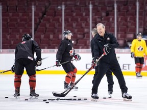 Canada's head coach Tim Hunter, front right, passes pucks during a drill during practice for the IIHF World Junior Hockey Championships, in Vancouver on Tuesday, Dec. 25, 2018. Canada is scheduled to play Denmark in their first game on Wednesday.