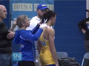 In this image taken from a Wednesday, Dec. 19, 2018 video provided by SNJTODAY.COM, Buena Regional High School wrestler Andrew Johnson gets his hair cut courtside minutes before his match in Buena, N.J., after a referee told Johnson he would forfeit his bout if he didn't have his dreadlocks cut off. Johnson went on to win the match after a SNJ Today reporter tweeted video if the incident, the state's Interscholastic Athletic Association says they are recommending the referee not be assigned to any event until the matter has been reviewed more thoroughly.