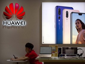 A sales clerk looks at his smartphone in a Huawei store at a shopping mall in Beijing Wednesday, July 4, 2018.