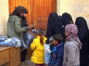 Members of the Islamic State distribute niqabs, enveloping black robes and veils that leave only the eyes visible, to Iraqi women in Mosul in this photo released on Jan. 31, 2014.