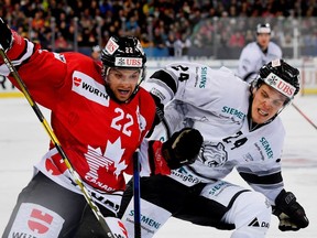 Team Canada's Zach Boychuk, left, and Ice Tigers's Marcus Weber, right, challenge for the puck during a Spengler Cup 2018 ice hockey match between Team Canada and Thomas Sabo Ice Tigers in Davos, Switzerland, Sunday, Dec. 30, 2018. (Gian Ehrenzeller/Keystone via AP) ORG XMIT: DSOB105