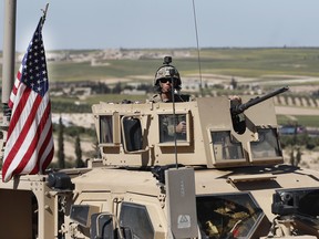 In this April 4, 2018 file photo, a U.S. soldier sits in an armoured vehicle on a road leading to the tense front line with Turkish-backed fighters, in Manbij, north Syria.