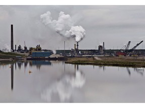 The Syncrude oil sands extraction facility is reflected in a tailings pond near the city of Fort McMurray, Alta., on June 1, 2014. Canadian environment groups are at the global climate change conference in Poland today calling out the federal government for allowing the oil and gas industry to systematically weaken Canada's efforts to be a climate leader. Environmental Defence and Stand Earth are among the groups releasing a report which shows emissions from the oil and gas sector continue to rise and intensive lobbying from the industry means about 80 per cent of those emissions will be exempt from the carbon price.