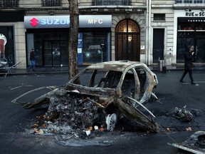 A charred car is pictured the day after a demonstration, near the Arc de Triomphe, in Paris, Sunday, Dec. 2, 2018. A protest against rising taxes and the high cost of living turned into a riot in the French capital, as activists torched cars, smashed windows, looted stores and tagged the Arc de Triomphe with multi-colored graffiti.