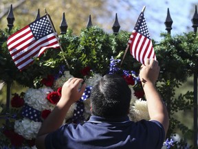 Erick Herrera makes sure the two small American flags are placed correctly on the presidential wreath on the gate outside of former President George H.W. Bush's residence on Saturday, Dec. 1, 2018, in Houston. Bush, who died late Friday at his Houston home at age 94, is to be honoured with a funeral service in the nation's capital on Wednesday, followed by burial Thursday at his presidential library in Texas.