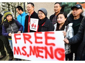 People hold a sign at a B.C. courthouse prior to the bail hearing for Meng Wanzhou, Huawei's chief financial officer on Monday. Meng was released on bail Tuesday.