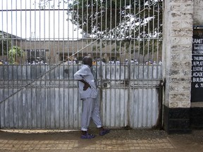 In this photo taken Thursday, Nov. 1, 2018, a prisoner taking a break from vocational training looks through a fence at others engaged in activities, at Kamiti Maximum Security Prison in Nairobi, Kenya. Many prisoners are illiterate and poor, with little resources to fight for themselves, but the African Prisons Project is helping some to master basic literacy and study law, turning them into their own legal advocates in countries where such assistance is desperately rare.