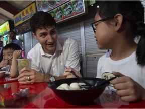 Prime Minister Justin Trudeau speaks with children as he visits the Adam road food centre in Singapore in November.  Trudeau has a family connection to Singapore, but he didn't tell the whole story.
