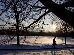 A person walks through a snow covered park.