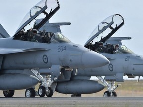 Royal Australian Air Force F-18 Hornet pilots wave to the crowd as they taxi down the runway after performing during the Australian International Airshow at the Avalon Airfield near Lara southwest of Melbourne on February 24, 2015.