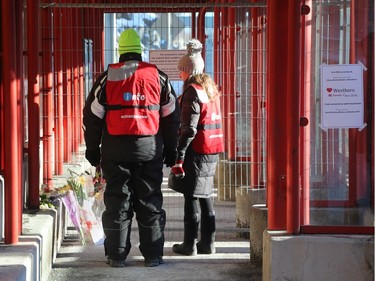 OC Transpo information workers look at some flowers that were left at the Westboro station in memory of the bus crash victims, January 14, 2019.