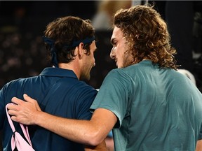 Switzerland's Roger Federer (R) speaks with Greece's Stefanos Tsitsipas after defeat in their men's singles match on day seven of the Australian Open tennis tournament in Melbourne on January 20, 2019.