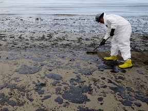 A worker removes oil from a beach.