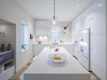 The kitchen is ultra modern in design with sleek white custom cabinets. A glass mural of flowers makes up the backsplash on the rear wall and was created by glass artist Delfina Falcão.