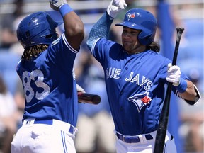 The Toronto Blue Jays' Vladimir Guerrero Jr., left, and Bo Bichette, right, celebrate after Bichette's two-run home run during the first inning of a spring training baseball game against the Canada Junior National Team Saturday, March 17, 2018, in Dunedin, Fla. Vladimir Guerrero Jr. and Bo Bichette are among the 15 players announced as non-roster invitees to the Blue Jays' major league spring training camp.
