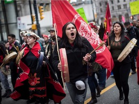 Alex Spence, centre, who is originally from Haida Gwaii, beats a drum and sings during a march in support of pipeline protesters in northwestern British Columbia, in Vancouver, on Tuesday.