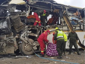 In this photo released by the Bolivian Police of Oruro, firefighters and police help a victim of a crash of two buses on the outskirts of Challapata, Bolivia, Saturday, Jan. 19, 2019. The crash killed over a dozen people and left several injured on a road in the Bolivian highlands, police said.