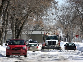 A sand truck plows the snow on a residential street.