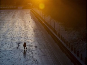 The rising sun reflects off a railing of the Corktown Footbridge as a skater makes their way along the Rideau Canal Skateway on Saturday.