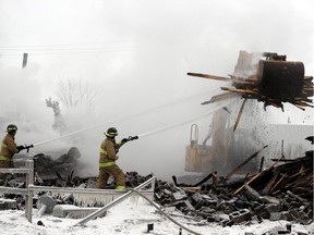 Thursday morning Pembroke firefighters Tom Watkins (left) and Luke Dunn doused hot spots on site of a massive fire at the Lavern Heideman and Sons lumber yard in Pembroke, which began around 8 p.m. Jan. 2. An investigator from the Office of the Fire Marshal arrived Thursday afternoon to try and determine the cause of the blaze, which caused extensive damage.