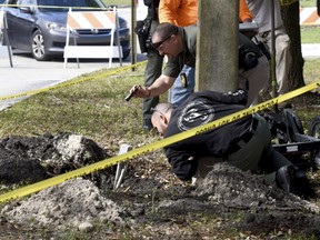 FBI and Pembroke Pines Police investigate a tunnel by a possible would-be bank robber which was discovered beneath the entrance to the Flamingo Pines shopping plaza Wednesday, Jan. 30, 2019, in Pembroke Pines, Fla.