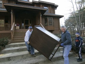 In this Monday, Jan. 14, 2019 photo, Kenny Lindsay, owner and auctioneer of Kenny Lindsay's American Eagle Auction and Appraisals Co., at left, and auction manager Bob Goetz help load a dresser to the car of high bidder Stacy Luoma of Redford after the close of the Gilbert/Busfield estate auction in Genoa Township, Mich. Giving guidance to the two is Lindsay's son Carson, who tells them when a step is coming.