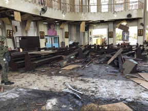 In this photo provided by WESMINCOM Armed Forces of the Philippines, a soldier views the site inside a Roman Catholic cathedral in Jolo, the capital of Sulu province in the southern Philippines after two bombs exploded Sunday, Jan. 27, 2019.