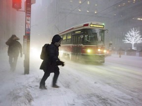 A person makes their way to a streetcar as snow flies through the air during a squall in downtown Toronto, on Thursday, December 15, 2016.