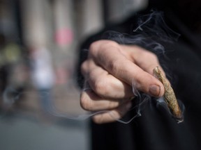 A person holds a joint while smoking marijuana to celebrate the legalization of recreational cannabis, in Vancouver, on Wednesday October 17, 2018.