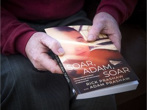 Rick Prashaw holds his book, Soar, Adam, Soar, the story of his transgender son's life.