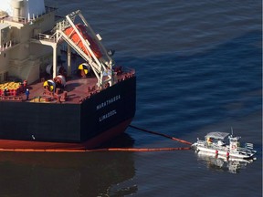 A spill-response boat secures a boom around the bulk-carrier cargo ship MV Marathassa after a bunker-fuel spill in Burrard Inlet in Vancouver on April 9, 2015.