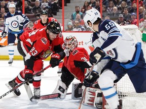 Anders Nilsson of the Ottawa Senators makes a pad save on a wraparound attempt by Mark Scheifele #55 of the Winnipeg Jets as Christian Jaros #83 of the Ottawa Senators defends the net in the first period on Saturday afternoon at the CTC.