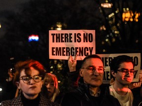 People hold protest signs in front of Trump International Hotel in New York City.