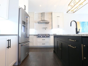 Timeless Shaker cabinets by Deslaurier Custom Cabinets are light on the perimeter and dark on the island, emphasizing the island as the centre of the room. Upgraded wide-planked hardwood flooring is carried through the kitchen from the adjacent great room.