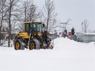 A city plow clears the parking lot of snow at the Fallowfield Transit Station following a winter storm in Ottawa on February 13, 2019.