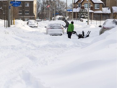 Residents struggle with the heavy snowfall on Sweetflag Street following a winter storm in Ottawa on February 13, 2019.
