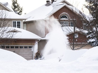 A man snowblows his driveway on Burntwood Avenue following a winter storm in Ottawa on February 13, 2019.
