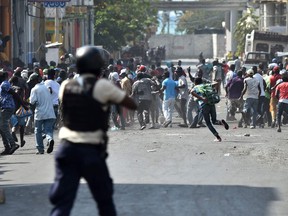 TOPSHOT - Demonstrators flee as Haitian Police open fire, during the clashes, in the centre of Haitian Capital Port-au-Prince, February 13, 2019. - This is the seventh day of protests against Haitian President Jovenel Moise and the misuse of the Petrocaribe fund.