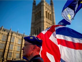 An anti-Brexit protester wearing a European Union flag cap, flies European and Union flags outside the Houses of Parliament in London on Feb. 21, 2019.