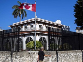 FILE - In this April 17, 2018 file photo, a  man walks beside Canada's embassy in Havana, Cuba.  Canada announced Wednesday, Jan. 30, 2019,  it is removing up to half of the Canadians at its embassy in Cuba after another diplomat was found to have fallen mysteriously ill. Canada has confirmed 14 cases of mysterious health problems since early 2017.