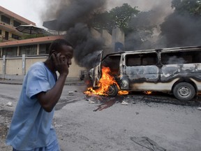 A man walks past a burning van torched by students who were protesting last week's fatal shooting of a graduate student, in Port-au-Prince, Haiti, Friday, Nov. 16, 2012. During the Friday protest another man was shot dead. Protesters responded to the shooting of the unidentified man by torching a van that was parked outside the university and setting fire to tire barricades and throwing rocks at U.N. peacekeepers and riot police patrolling the area.