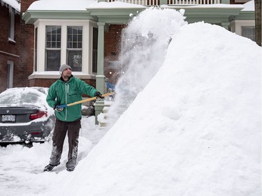 James Liston throws snow onto a massive snow pile as he helps clear snow from a neighbour's driveway in Ottawa's Glebe neighbourhood during a winter storm on Wednesday, Feb. 13, 2019. The storm, which began on Tuesday afternoon, is expected to bring 30-40 centimetres of snow by Wednesday. All Ottawa-area schools are closed and classes were cancelled for a 24 hour period at the University of Ottawa and Carleton University.