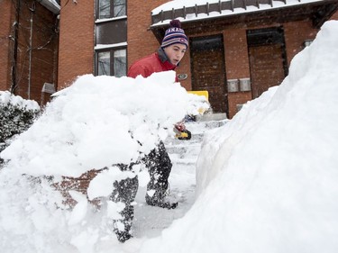 Sam Kuntz clears snow from a walkway in Ottawa's Glebe neighbourhood during a winter storm on Wednesday, Feb. 13, 2019. The storm, which began on Tuesday afternoon, is expected to bring 30-40 centimetres of snow by Wednesday. All Ottawa-area schools are closed and classes were cancelled for a 24 hour period at the University of Ottawa and Carleton University.