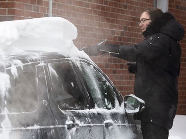 Nick Carman brushes snow that accumulated overnight off the roof of his car during a winter storm in Ottawa on Wednesday, Feb. 13, 2019. The storm, which began on Tuesday afternoon, is expected to bring 30-40 centimetres of snow by Wednesday. All Ottawa-area schools are closed and classes were cancelled for a 24 hour period at the University of Ottawa and Carleton University.
