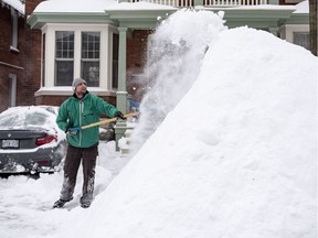 James Liston throws snow onto a massive snow pile as he helps clear snow from a neighbour's driveway in Ottawa's Glebe neighbourhood during the winter storm on Wednesday, Feb. 13,