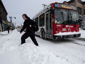 A man crosses a snowbank after getting off an OC Transpo bus in Ottawa's Glebe neighbourhood during the winter storm on Wednesday, Feb. 13, 2019.